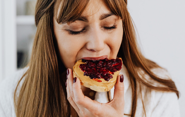 Dame au cheveux châtain qui mange une tartine